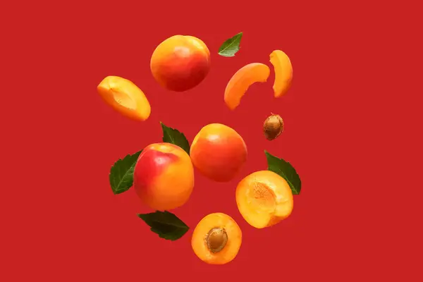 Flying Fresh Apricots Pieces Leaves Red Background — Stock Photo, Image