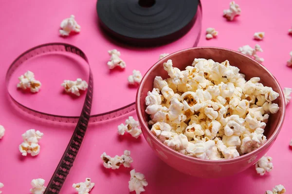 Schüssel Mit Leckerem Popcorn Und Filmrolle Auf Rosa Hintergrund — Stockfoto