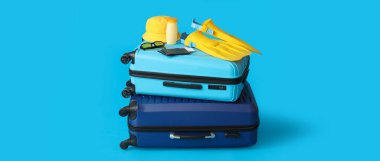 Plaj aksesuarlı bavullar, pasaportlar ve açık mavi arka planda biletler