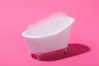 Pembe arka planda köpüklü küçük küvet.