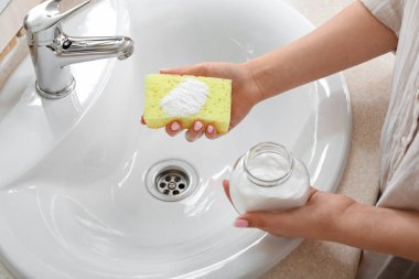 Kabartma tozu ve süngerle lavaboyu temizleyen kadın.