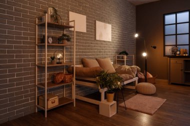 Karanlık oturma odasının içinde kanepe, raflar ve parlak lambalar var.