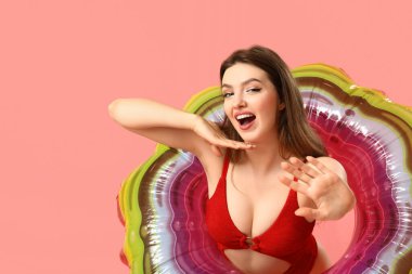 Pembe arka planda yüzen genç bir kadın.