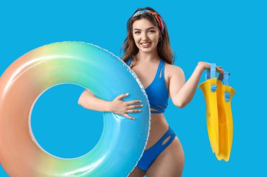 Yüzme yüzüğü ve mavi arka planda paletleri olan genç bir kadın.