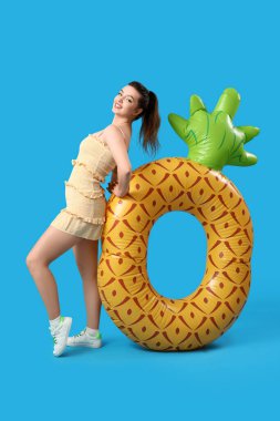 Mavi arka planda ananas şeklinde yüzen genç bir kadın.