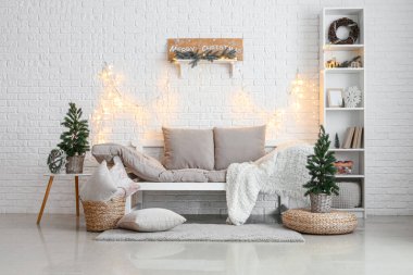 Oturma odasının içinde Noel ağaçları, kanepe ve parlayan ışıklar var.