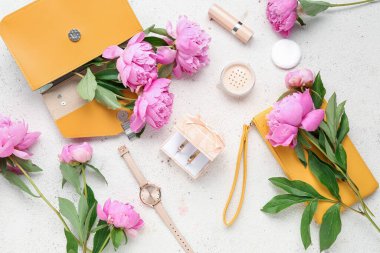 Alyanslı kompozisyon, kadın aksesuarları, kozmetik ürünleri ve açık arkaplanda güzel şakayık çiçekleri.