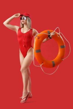 Female lifeguard with ring buoy on red background