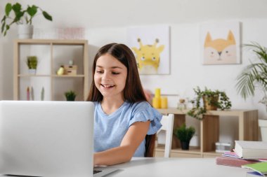 Evde bilgisayar dersi alan küçük bir kız.