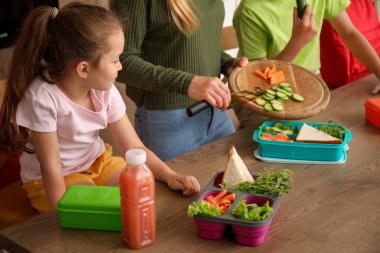 Anne, küçük çocuklarına mutfakta öğle yemeği hazırlıyor.