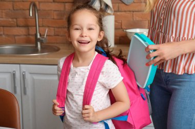 Anne, küçük kızı için mutfakta öğle yemeği hazırlıyor.