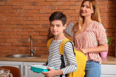 Anne, küçük oğlu için mutfakta öğle yemeği hazırlıyor.