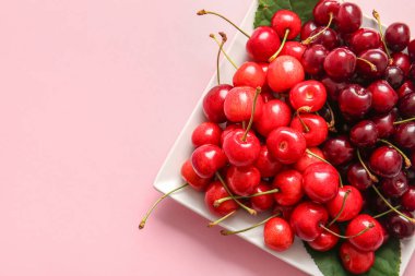 Pembe arka planda tatlı kirazlı tabak