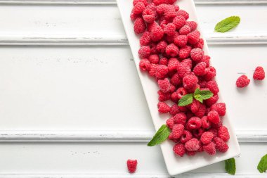 Taze ahududu tabağı ve beyaz arka planda nane şekeri.