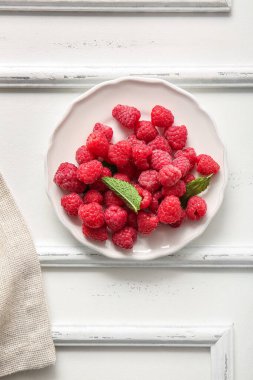 Taze ahududu tabağı ve beyaz arka planda nane şekeri.