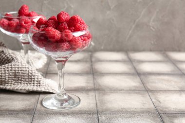 Gri fayansların üzerinde taze ahududu olan bardaklar.