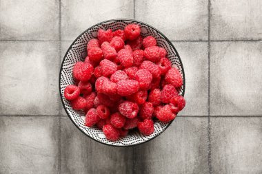 Gri fayans masasında taze ahududu kasesi.