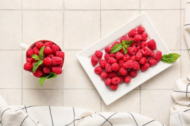 Beyaz fayanslı taze ahududu dolu fincan ve tabak.