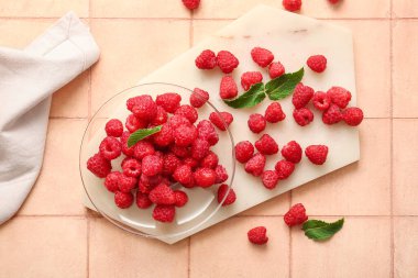 Taze ahududu ve pembe fayans üzerinde nane şekerli cam tabak.