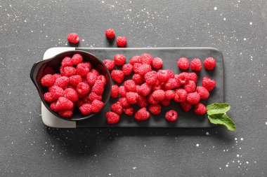 Siyah arka planda taze ahududu olan bir kase ve yemek.