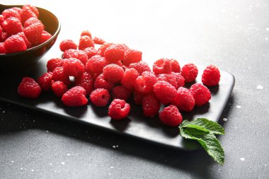 Siyah arka planda taze ahududu olan bir kase ve yemek.