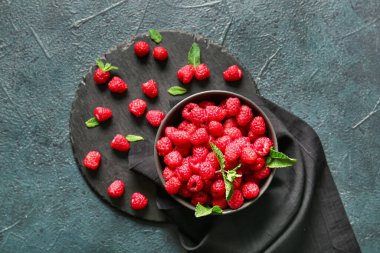 Koyu arkaplanda taze ahududu olan kase ve yemek.