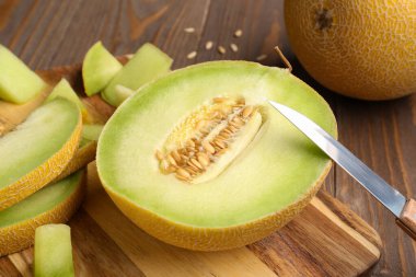 Tahtada yarım tatlı kavun ve ahşap arka planda parçalar, yakın plan.