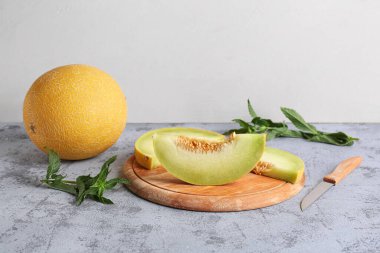 Tatlı kavun ve tahta tahta, gri masa üzerinde parçalar.