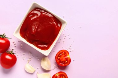 Domates ezmeli kase ve leylak arkaplanda taze sebzeler.