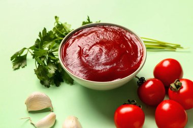 Yeşil arka planda domates ezmeli ve taze sebzeli kase.