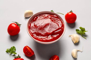 Domates ezmeli kase ve gri arka planda taze sebzeler.