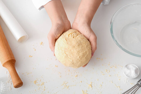 Woman kneading dough for Italian Grissini at white table in kitchen