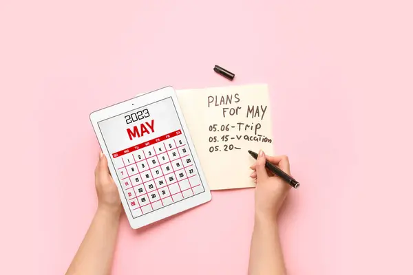 持有带有日历和五月粉红背景书写计划的平板电脑的女性 — 图库照片