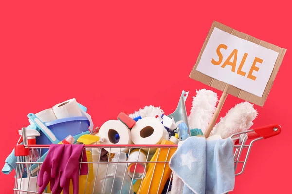 赤い背景に単語Saleと掃除用品でいっぱいのショッピングカート — ストック写真