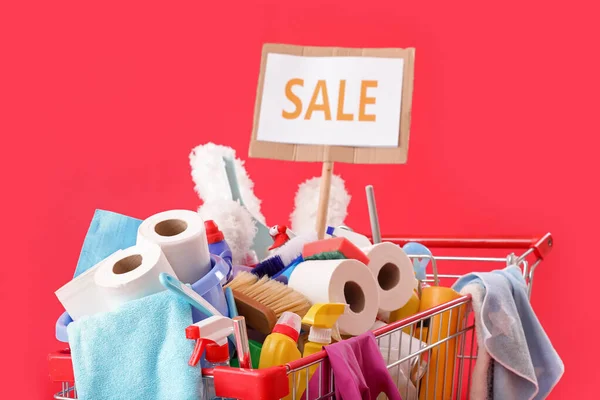 掃除用品や単語でいっぱいのショッピングカート赤い背景で販売 — ストック写真