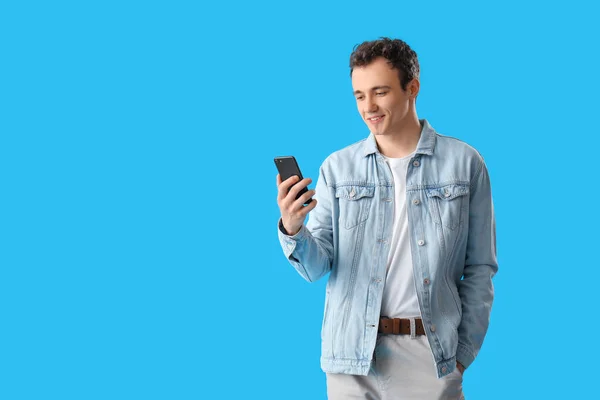 青い背景にスマートフォンを持つ若い男 — ストック写真