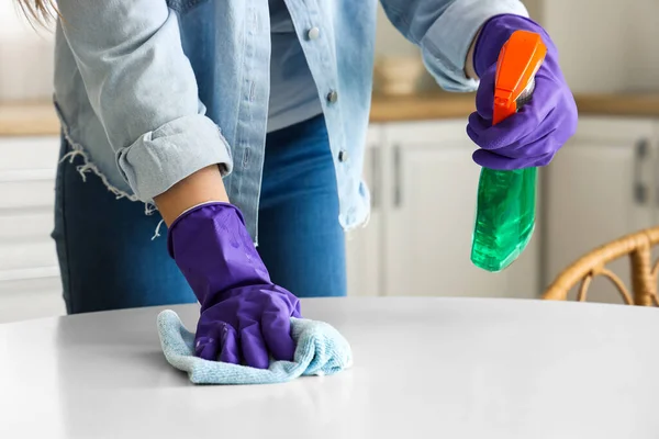 穿着紫色橡胶手套的女人用抹布和洗涤剂擦拭桌子 — 图库照片