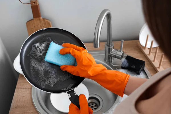身穿橙色橡胶手套的妇女用海绵清洗油锅 — 图库照片