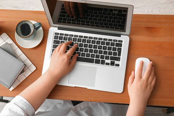 女程序员在木制桌子上使用带有咖啡和鼠标的笔记本电脑 — 图库照片