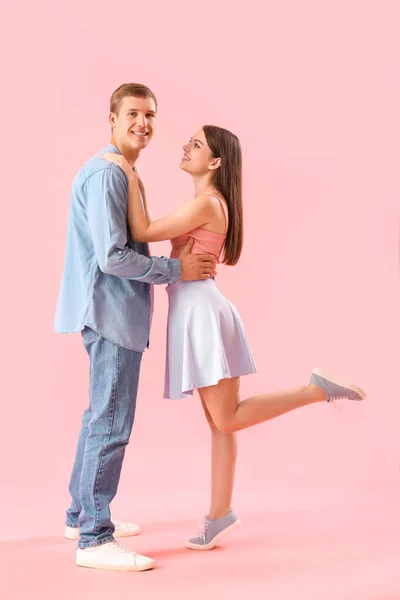 快乐的年轻夫妇抱着粉红的背景 — 图库照片