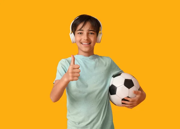 Kleiner Junge Kopfhörer Mit Fußballball Daumen Hoch Auf Orangefarbenem Hintergrund — Stockfoto
