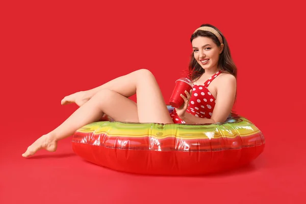 拿着苏打水和红色背景的泳圈的年轻女人 — 图库照片
