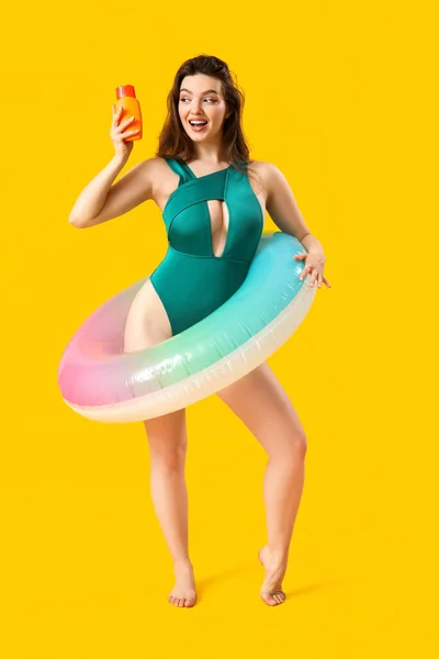Junge Frau Mit Sonnencreme Und Schwimmring Auf Gelbem Hintergrund — Stockfoto