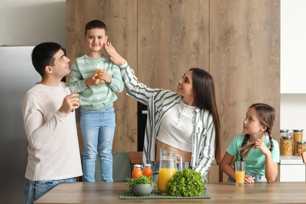 快乐的父母和他们的孩子在厨房里喝橙汁 — 图库照片