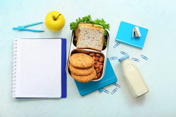 stock image Stationery, drink and lunch box with tasty food on blue background