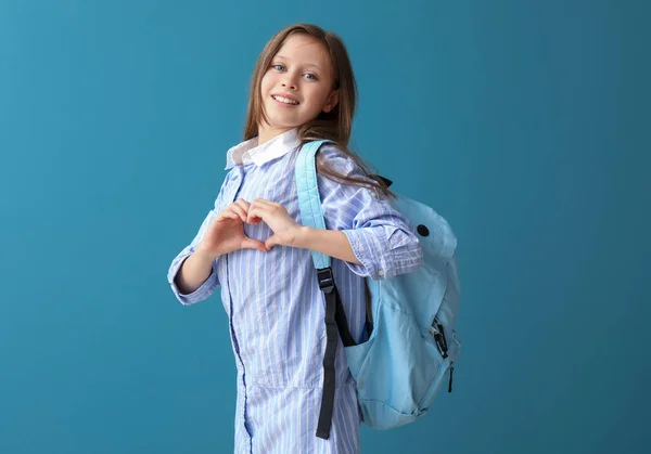 Mała Uczennica Plecakiem Robi Gest Serca Niebieskim Tle — Zdjęcie stockowe