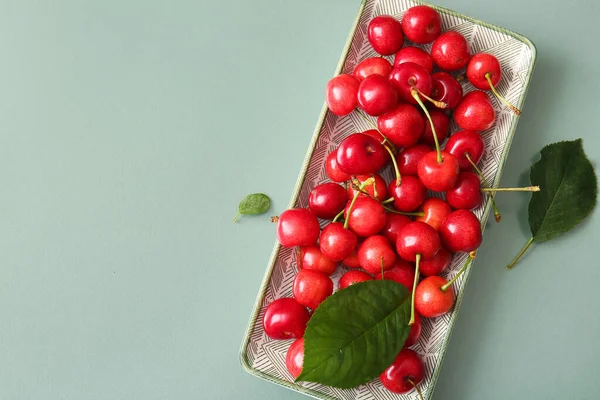 Stock image Plate with sweet cherries on green background