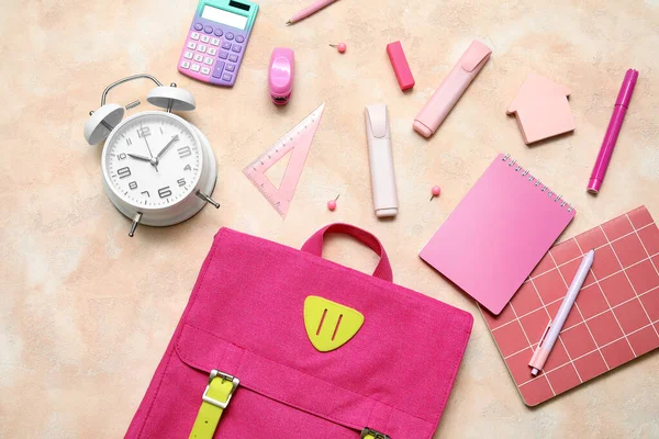 米色背景的带闹钟 计算器和文具的粉红校园背包 — 图库照片