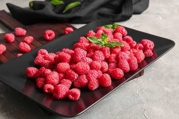 stock image Plate with fresh raspberries and mint on grey background