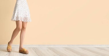 Bej duvarın yanında şık sandaletli bir kadın. Tasarım için pankart